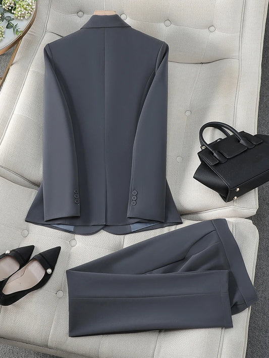 Gray suit jacket and pants on a white chair with black shoes and handbag.