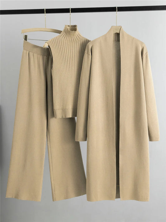 Beige outfit with sweater, coat, and pants on hangers against a gray background